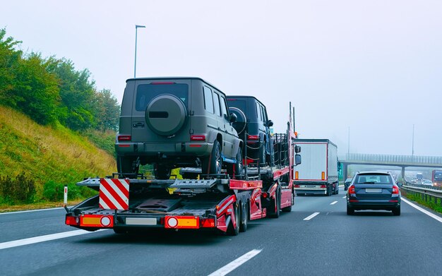 Photo cars carrier truck in road or highway of slovenia. lorry transporter at logistics work. trailer with cargo car drive. delivery for transport export industry. heavy hauler. haul vehicle. auto haulage.