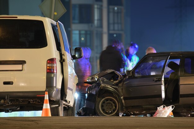 Cars crashed heavily in road accident after collision and silhouette of people on city street at night Road safety and insurance concept