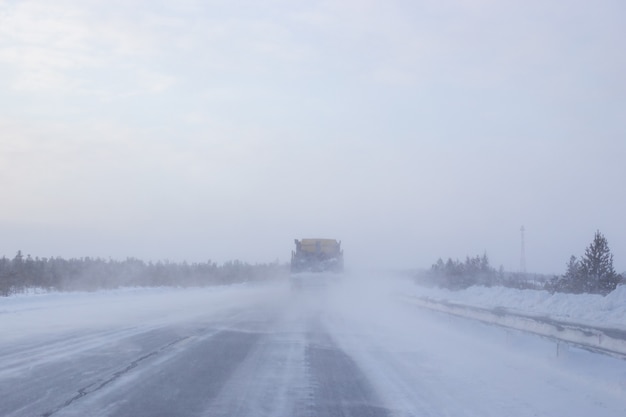 Cars go on a winter road with poor visibility, weather and snowstorm