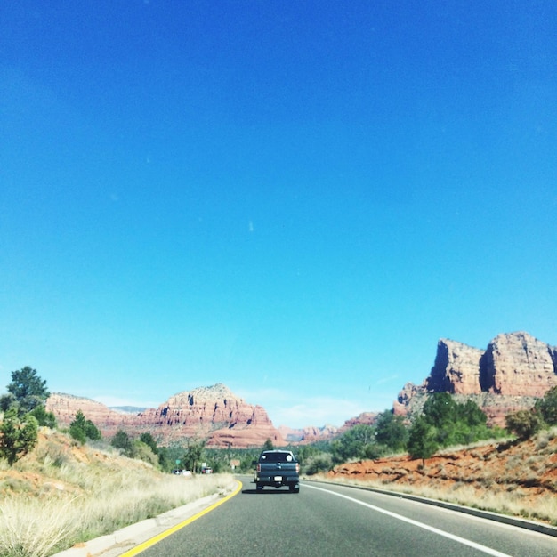 Cars on highway against clear blue sky