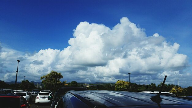 Cars moving on road against cloudy sky