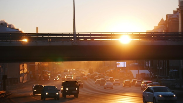 橋の夕日の下で道路に乗っている車