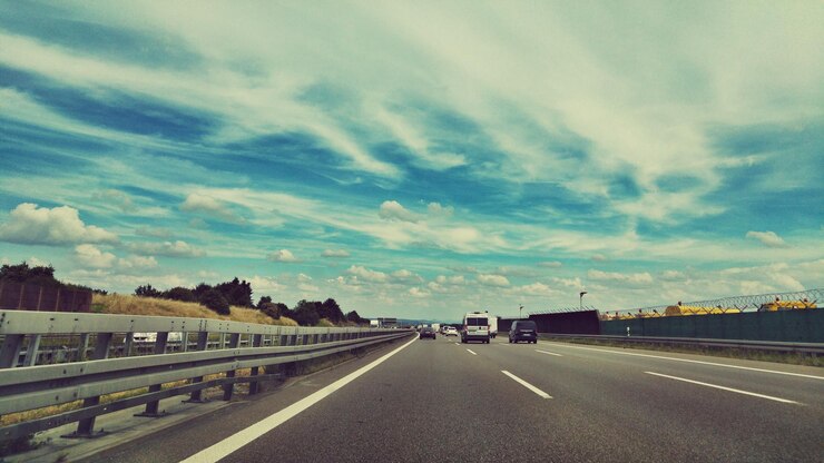 Photo 雲の空に逆らって道路を走る車