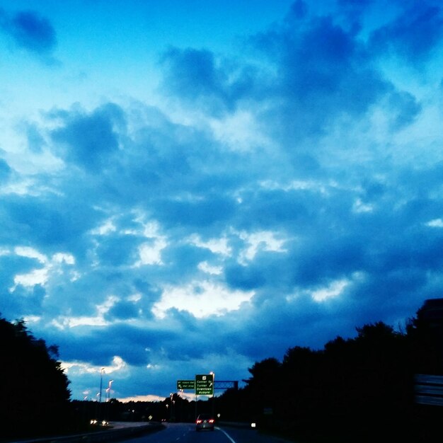 Foto auto sulla strada contro un cielo nuvoloso