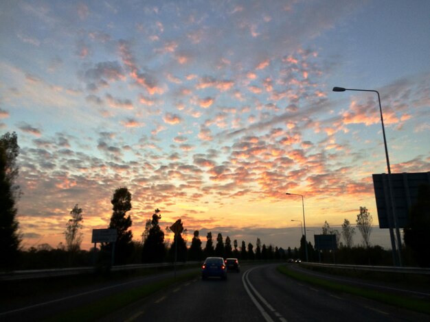 Cars on road against sky during sunset