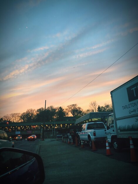 Cars on road against sky during sunset