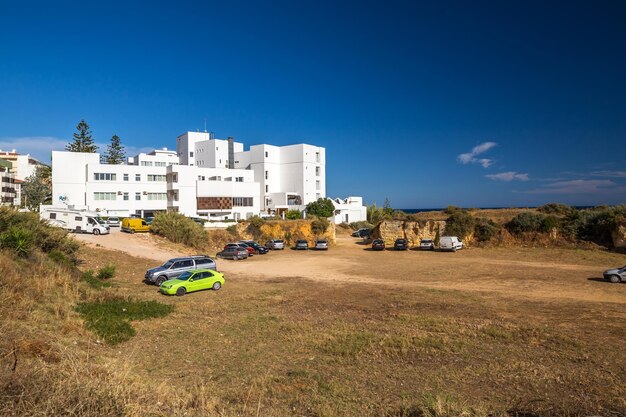 Cars on road by buildings against blue sky