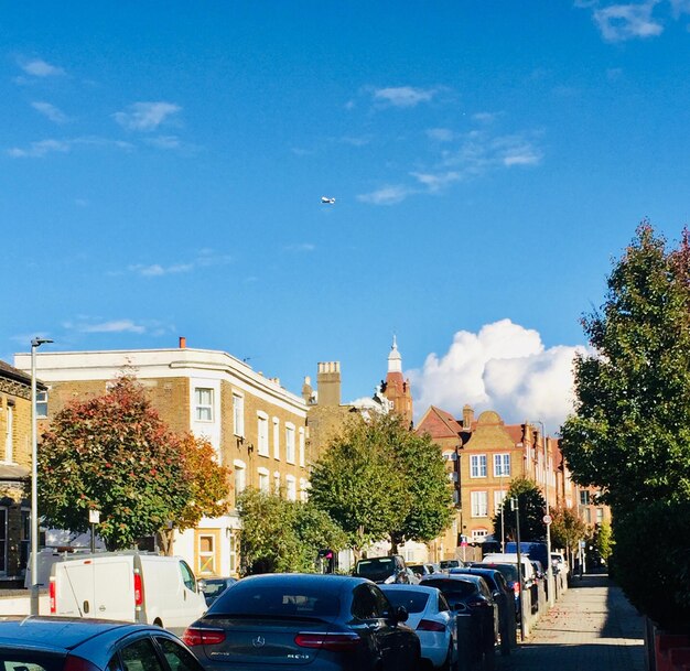 Cars on road by buildings against blue sky