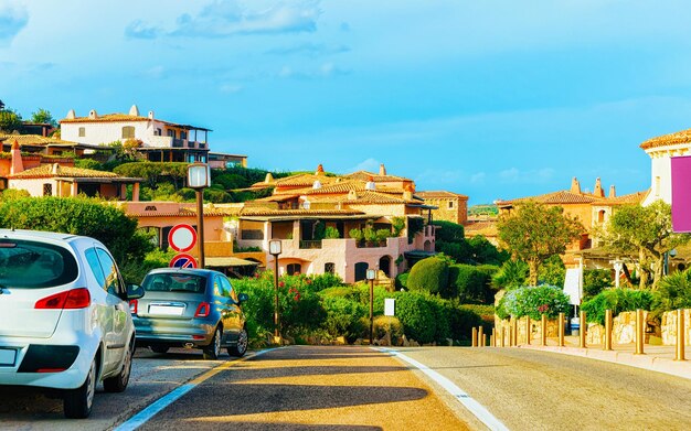 이탈리아 여름 사르데냐 섬의 코스타 스메랄다(Costa Smeralda)에 있는 포르토 체르보(Porto Cervo) 도로에 자동차. 운송 유럽의 고속도로에서 운전. 고속도로에서 자동차의 보기입니다. 올비아 지방. 혼합 매체.