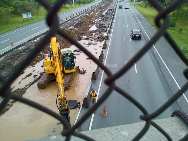 Photo cars on road seen through chainlink fence