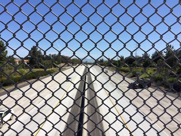 Foto auto sulla strada viste attraverso la recinzione a catena