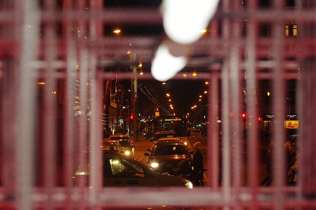 Автомобили на дороге, видные сквозь окно ночью