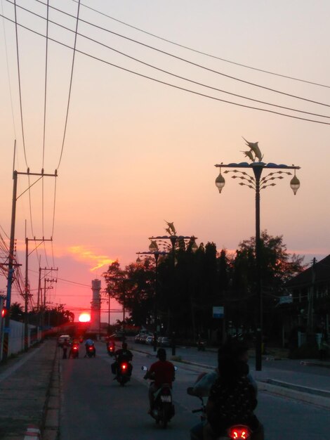 Cars on street against sky at sunset