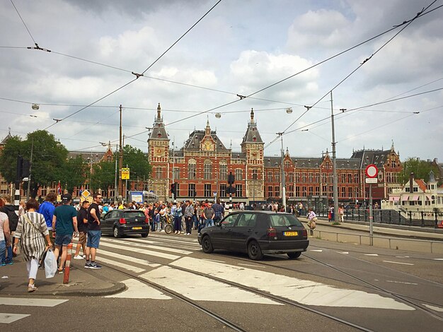 Photo cars on street by amsterdam centraal against cloudy sky