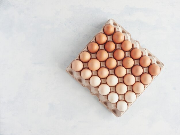 Carton egg box with many brown eggs in diferents colours and degradient tones top view