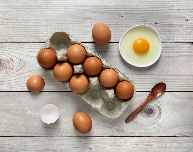 Photo carton of eggs cracked eggshell yolk on wooden background top view flat lay