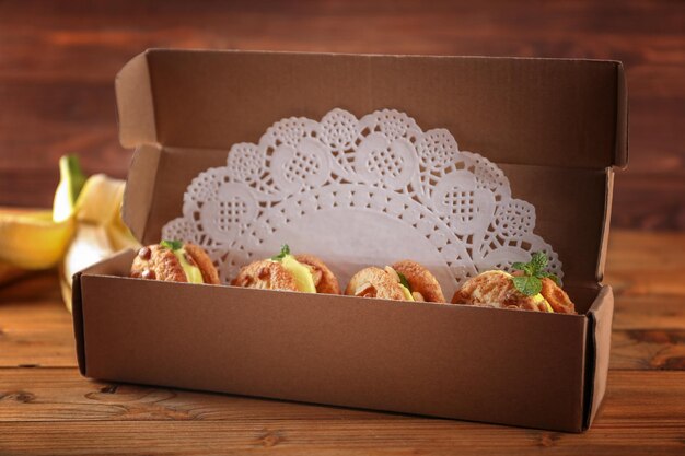 Foto cartoon doos met heerlijke citroen-ijs koekjes sandwiches op houten tafel close-up