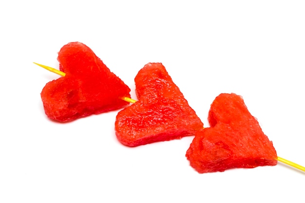 Carved from watermelon slices in shape of hearts on white background.