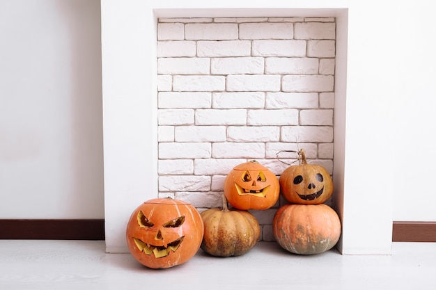 Carved Halloween pumpkins lanterns next to fireplace at home