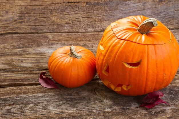 Carved orange scary halloween pumpkin on aged wooden table