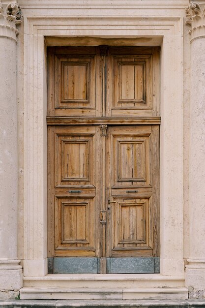 Foto porta in legno scolpita di un'antica chiesa con colonne e stucco