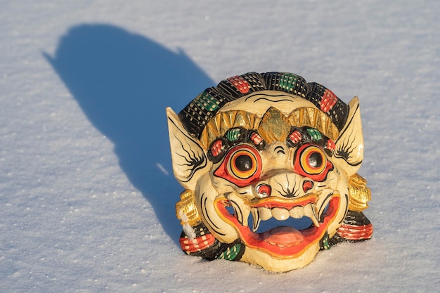 Carved wooden mask on a white snow in winter