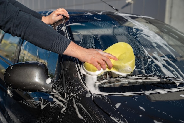 Carwash concept man wash car with soap and yellow sponge