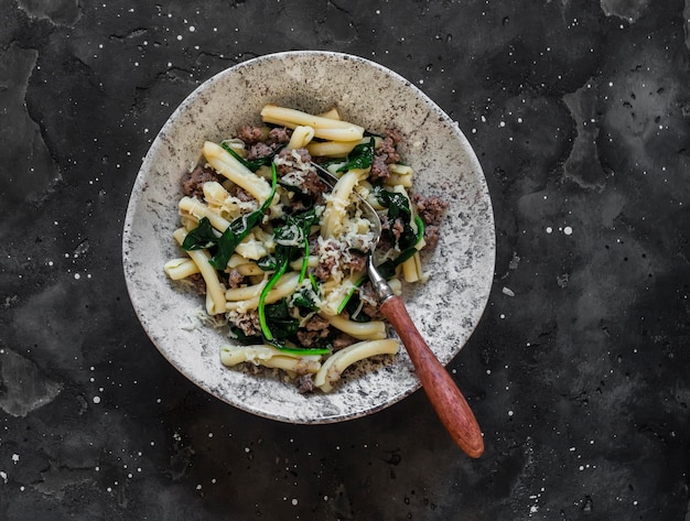 Casarecce pasta met gehakt en spinazie op een donkere achtergrond bovenaanzicht