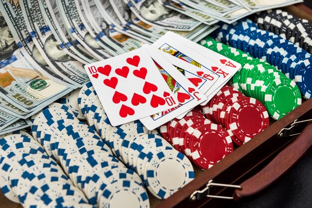 a case full of chips, dollars and playing cards on black