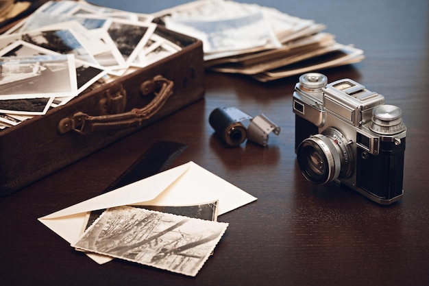 Case with old black and white photographs film camera and film\
reel old photos on foreground