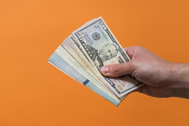 Cash dollars in hand on orange background