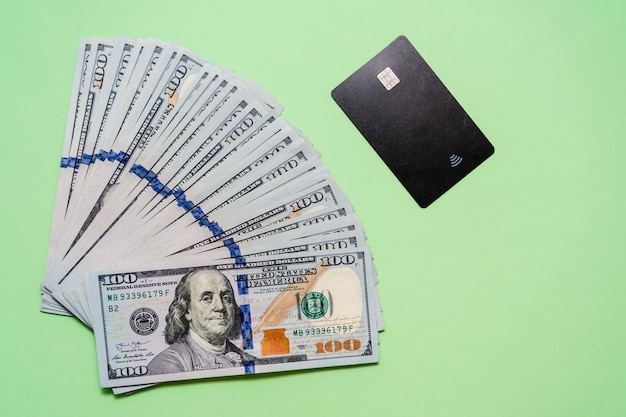 Cash of dollars with credit card on green background