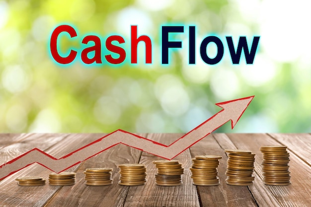 Cash Flow concept Illustration of upward arrow and stacked coins on wooden table against blurred green background