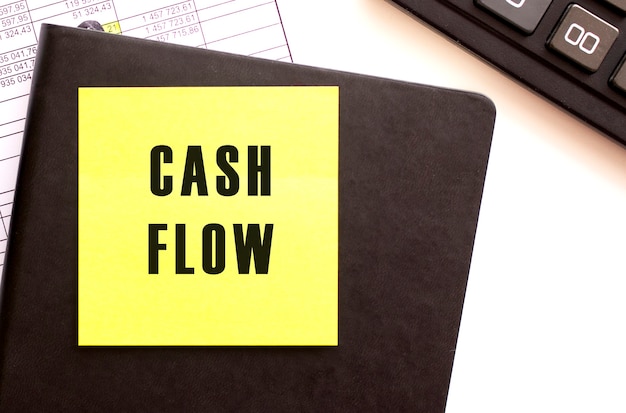 CASH FLOW tekst op een sticker op uw bureaublad Dagboek en rekenmachine