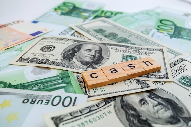 Cash inscription on wooden cubes on the texture of us dollars and euro banknotes