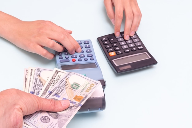 Cash payment concept. A hand giving cash for a purchase, a hand pressing buttons on a cash register, and calculating the cost on a calculator. Calculation and payment of taxes. Black Friday concept