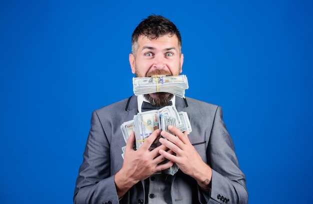 Cash transaction business Easy cash loan Man formal suit hold many dollar banknotes blue background Businessman got cash money Take my money Gain real money Richness and wellbeing concept