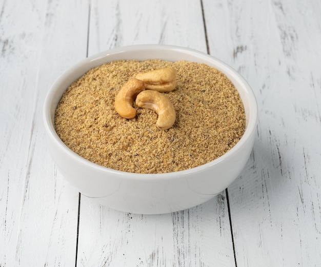 Cashew nut flour in a bowl over wooden table. Gluten free flour.