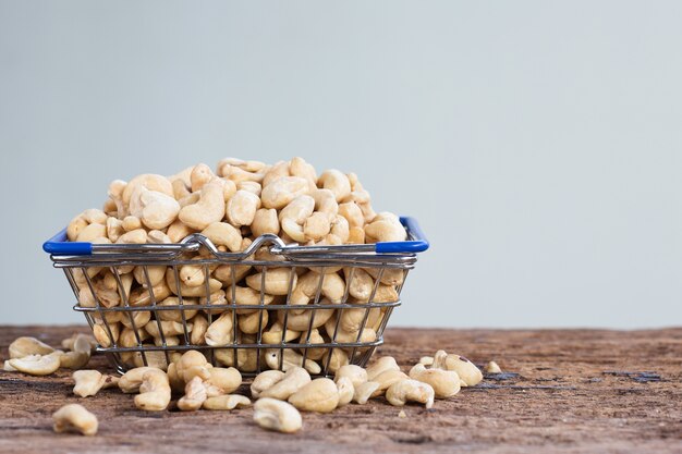 Cashew nuts in basket on wooden table with copy space.