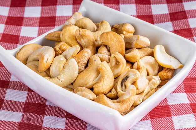 Cashew nuts in crockery jar on checkered fabric background