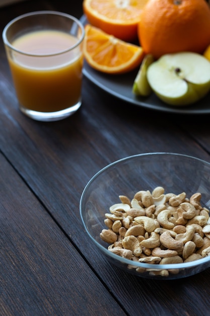 Cashew nuts and juice next to other fruits on a black wooden table