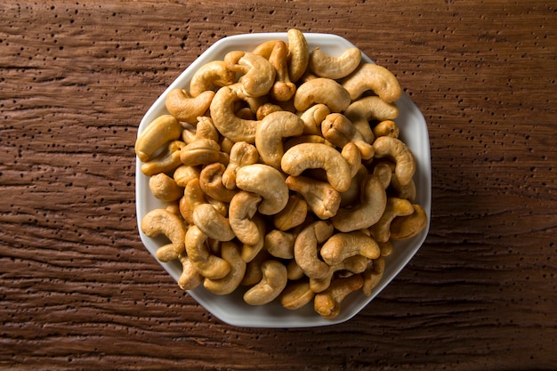 Cashew nuts in white bowl on wood background
