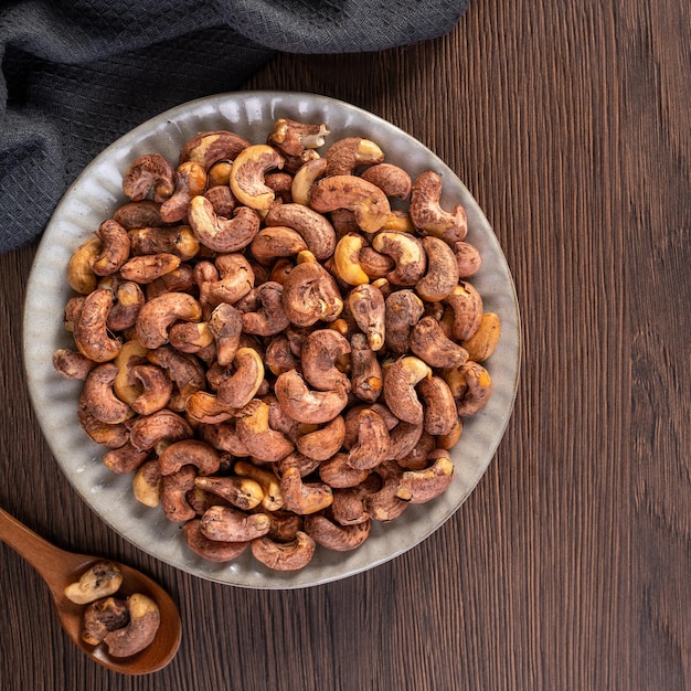 Cashew nuts with peel in a plate on wooden tray and table background healthy raw food plate