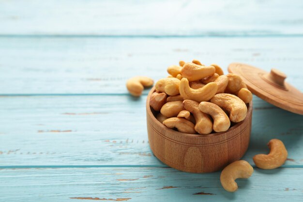 Cashew nuts on wooden bowl on blue background. Top view.