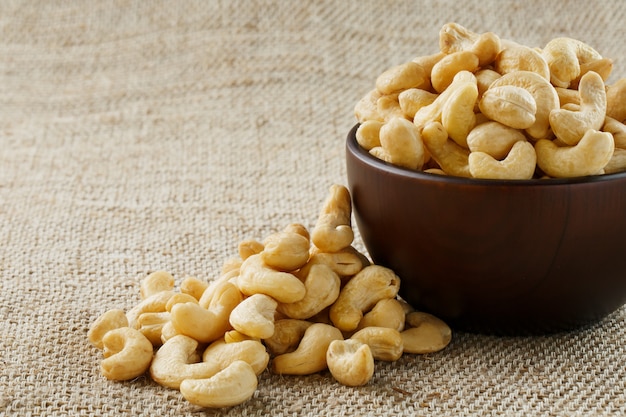 Cashew nuts in a wooden bowl on a burlap cloth background