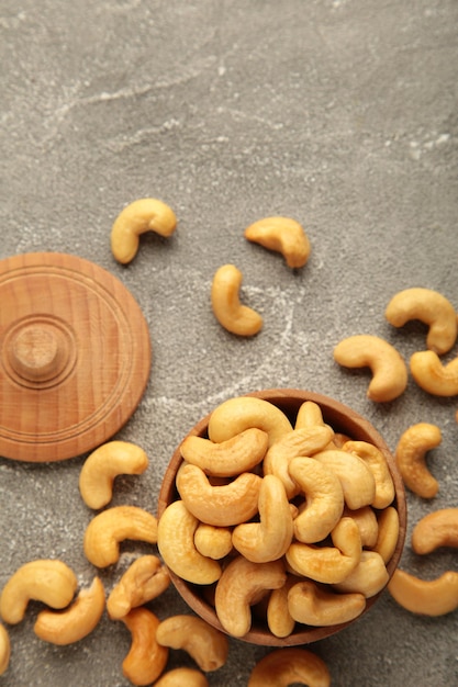 Cashew nuts on wooden bowl on grey background. Vertical photo.