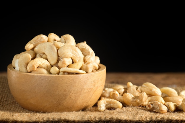 Cashew nuts on wooden bowl with dark background.