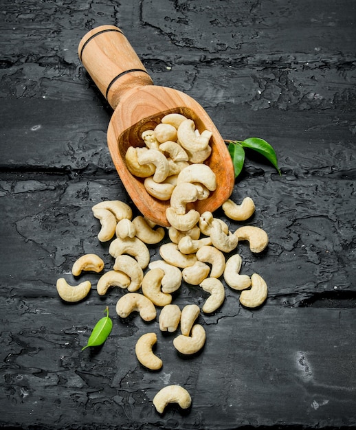 Cashew nuts in a wooden scoop with leaves