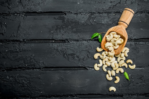 Cashew nuts in a wooden scoop with leaves