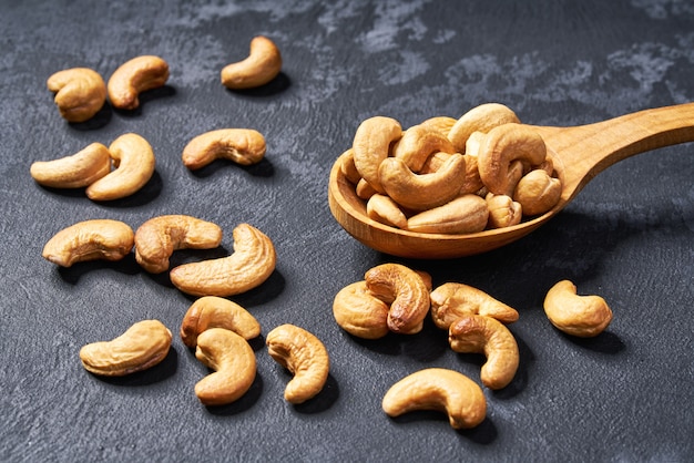 Cashew nuts  in wooden spoon  on black table,close-up